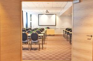 a conference room with tables and chairs and a projection screen at Centennial Nexus Hotel Tallinn in Tallinn