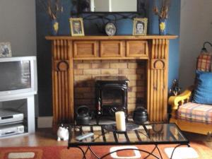 Ryebrook House في كيلارني: غرفة معيشة بها موقد وطاولة بها شمعة