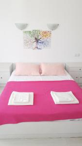 ein weißes Bett mit rosa Bettwäsche und zwei weißen Handtüchern in der Unterkunft Ayvalık Pansiyon in Ayvalık