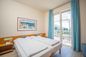 1 dormitorio con cama y ventana grande en Club Hotel Olivi - Tennis Center, en Malcesine