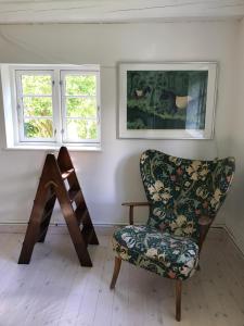 uma cadeira num quarto com duas janelas em Apple Cottage em Vejby