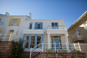 a white house with blue windows and a staircase at The Majestic Apartments in Kalk Bay