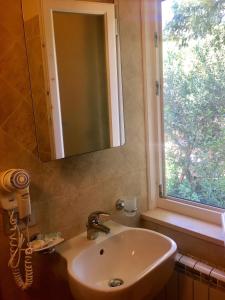 La salle de bains est pourvue d'un lavabo avec miroir et d'une fenêtre. dans l'établissement Bed & Breakfast Bounty, à Rio nellʼElba