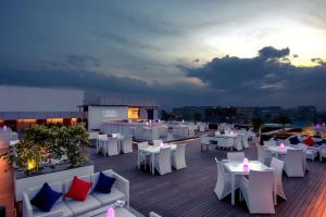 a rooftop restaurant with white tables and chairs at Feathers- A Radha Hotel, Chennai in Chennai