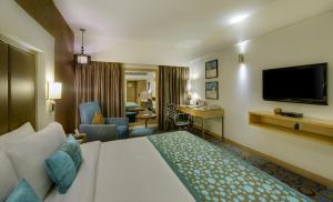um quarto de hotel com uma cama e uma sala de estar em Pride Plaza Hotel, Ahmedabad em Ahmedabad