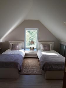 a attic room with two beds and a window at Dreilini Residence in Dreiliņi