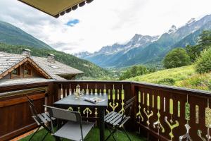 une table et des chaises sur un balcon avec des montagnes dans l'établissement APARTMENT REFUGE DE BELLACHAT - Alpes Travel - Les Houches - Sleeps 4, aux Houches