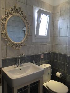een badkamer met een wastafel, een toilet en een spiegel bij Mike'sPlace in Antiparos Stad