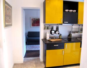 パリにあるUn nid spacieux à Bellevilleのキッチン(黄色のキャビネット、黒いカウンタートップ付)