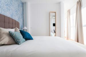 a bedroom with a large white bed with blue wallpaper at Hostly Acetres 1B-2B Center-Fibre-Conmunal terrace-Parking Optional in Seville