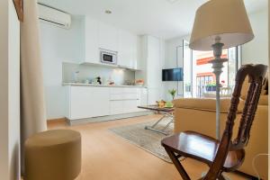 a living room with a chair and a kitchen at Hostly Acetres 1B-2B Center-Fibre-Conmunal terrace-Parking Optional in Seville