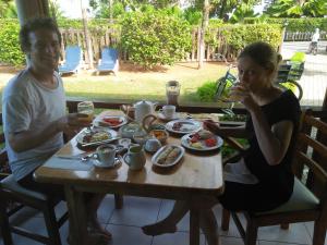 un hombre y una mujer sentados en una mesa comiendo comida en Villa Creole, en La Digue