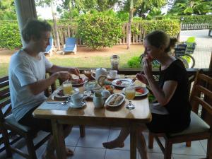 Ein Mann und eine Frau sitzen am Tisch und essen Essen. in der Unterkunft Villa Creole in La Digue