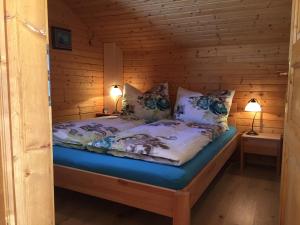 uma cama num chalé de madeira com duas luzes acesas em Almhaus Hochrindl em Hochrindl