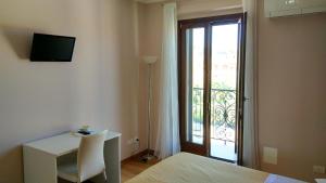 a bedroom with a bed and a desk and a balcony at La marina in San Benedetto del Tronto