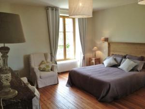 a bedroom with a bed and a chair and a window at Le Grand Arbre in Bayeux