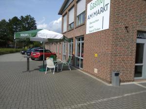 Gasthof am Markt في Edewecht: طاولة وكراسي ومظلة خارج المبنى