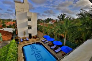 an aerial view of a resort with a swimming pool and blue umbrellas at St.Lachlan Hotel & Suites in Negombo