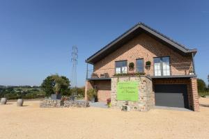 una casa de ladrillo con un cartel delante de ella en Les Coteaux du Vinave, en Herve