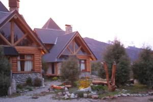 una casa de madera con montañas en el fondo en Cabañas Lemu Hue en San Carlos de Bariloche