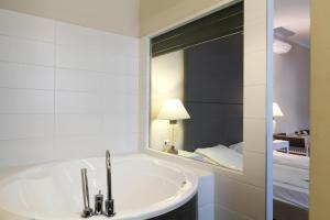 ein Bad mit einer Badewanne und einem Spiegel in der Unterkunft House Octogon in Budapest