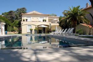 a house with a swimming pool with chairs in front of it at Sainte Maxime Studio 2 in Sainte-Maxime