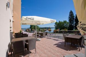 eine Terrasse mit Tischen, Stühlen und einem Sonnenschirm in der Unterkunft Hotel Slanica in Námestovo
