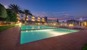 a swimming pool at night with a hotel in the background at Hotel LIVVO Corralejo Beach in Corralejo
