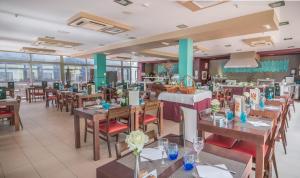 a restaurant with wooden tables and chairs and windows at Hotel LIVVO Corralejo Beach in Corralejo