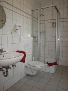 a bathroom with a toilet and a shower and a sink at Hotel Societät in Emmerich