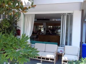 2 Stühle und eine Couch in einem Zimmer mit Pflanzen in der Unterkunft Hotel Meublè Villa Patrizia in Grado