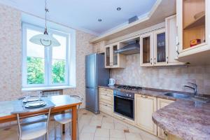 eine Küche mit einem Kühlschrank aus Edelstahl und einem Tisch in der Unterkunft Apartments Roomer 2 in Minsk