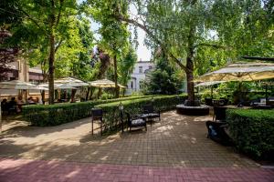a patio with tables and chairs and umbrellas in a park at Best Western Central Hotel in Arad