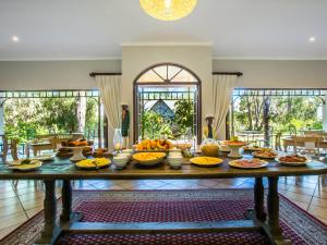 a table with a bunch of food on it at Hlangana Lodge in Oudtshoorn
