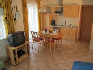 kuchnia i jadalnia ze stołem i telewizorem w obiekcie Appartement Millennium w mieście Bad Gastein