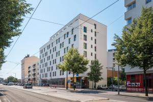 een hoog wit gebouw in een stadsstraat bij Résidence Ôtelia Affaires & Bien-être in Lyon