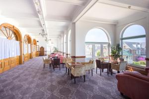 una stanza con tavoli, sedie e finestre di Legacy Hotel Victoria a Newquay