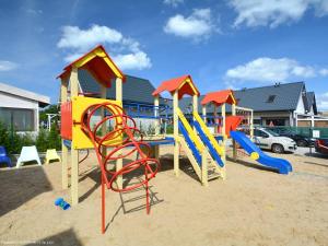 a playground with colorful play equipment in the sand at Domki letniskowe La Familia in Sianozety