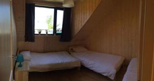 two beds in a small room with a window at Domki letniskowe La Familia in Sianozety