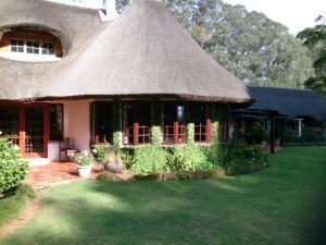 uma casa com telhado de palha e um quintal em Little Milton em Nottingham Road