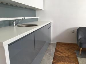 a white kitchen with a sink and a chair at Apartment Silver Pedestrian Zone in Belgrade +3 photos