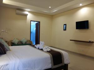 ein Schlafzimmer mit einem Bett und einem Fernseher an der Wand in der Unterkunft Darra Ria Villa Ubud in Ubud