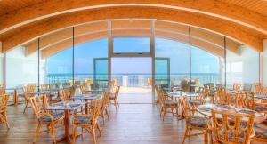 a restaurant with tables and chairs and a view of the ocean at Regent's Hotel in Lido di Jesolo