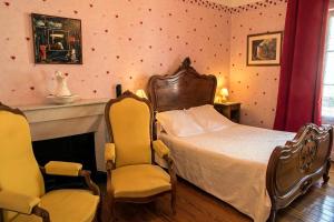 sypialnia z łóżkiem i 2 krzesłami w obiekcie Hôtel Restaurant Les Touristes w mieście Vals-les-Bains