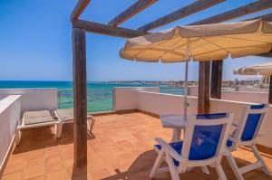 a balcony with chairs and an umbrella and the ocean at Hotel LIVVO Corralejo Beach in Corralejo