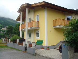 żółty budynek z drewnianymi balkonami w obiekcie Appartement Millennium w mieście Bad Gastein
