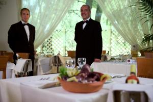 two men in tuxedos standing at a table in a restaurant at Hotel Portonuovo in Vieste