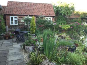 um jardim em frente a uma casa com plantas em Moat Cottage Barns em Corby