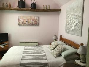 Moat Cottage Barns في كوربي: غرفة نوم بسرير ودهان على الحائط