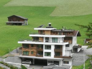 ein großes weißes Gebäude mit einem grünen Feld dahinter in der Unterkunft Alps Tux in Tux